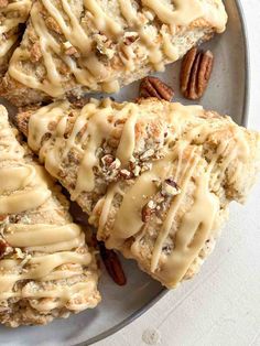 several pieces of bread with icing and pecans on a plate