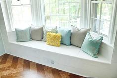 a white window seat with pillows on it