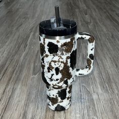 a black and white animal print coffee cup on a wood floor with a straw in it