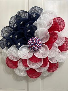 a patriotic wreath hanging on a door with red, white and blue mesh netting around it