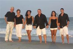 a group of people standing next to each other on top of a beach near the ocean