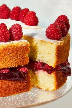 the cake has raspberries on it and is cut in half to show the layers