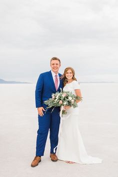 a bride and groom posing for a photo on the beach