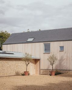 a house with two trees in front of it and a brick wall around the building