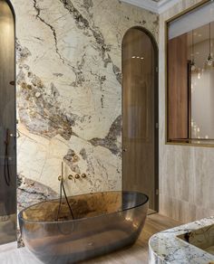 a bathtub in the middle of a bathroom with marble walls and flooring on both sides