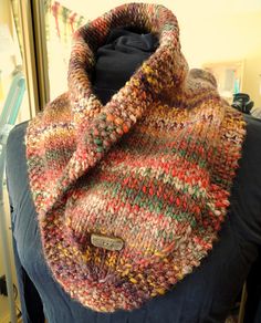 a multicolored knitted scarf sitting on top of a blue chair in front of a mirror