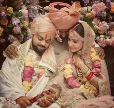 a man and woman sitting next to each other in front of some flowers on the ground