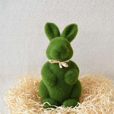 a green stuffed rabbit sitting on top of hay