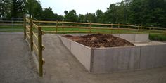 a large pile of dirt sitting in the middle of a parking lot next to a fence