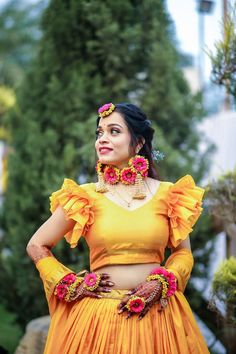 a woman in an orange outfit with flowers on her head and hands behind her back