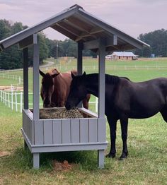 two horses are eating hay out of a feeder