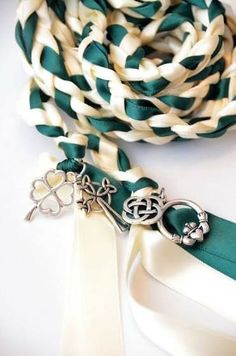 a green and white lanyard with two silver charms on it's end, next to a pair of scissors