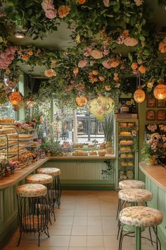 the inside of a flower shop with lots of flowers hanging from the ceiling and stools