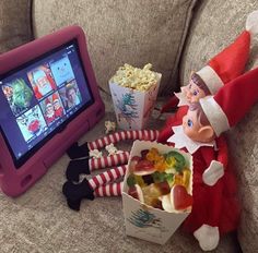 an elf is sitting on the couch next to a box of candy and a tablet