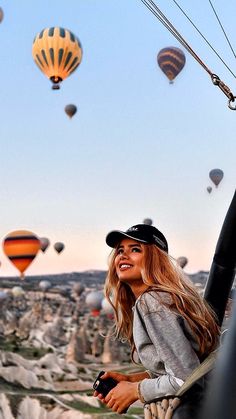 a woman standing on top of a hill next to hot air balloons