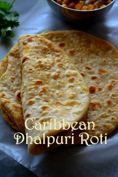 two flat breads sitting on top of a white paper next to a bowl of chickpeas