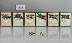 four christmas cards with pine cones and bows on them, sitting in front of a wall outlet