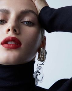 a woman with red lipstick and silver earrings