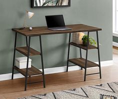 a laptop computer sitting on top of a wooden desk in front of a green wall