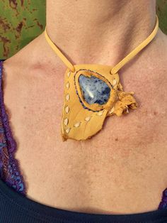 Gorgeous tear drop blue Sodalite gemstone is secured by hand stitching with blue artificial sinew.  Set in soft buckskin gold deerskin leather with raw edge detail.  Guaranteed unique!  I hand buckstitched the edges with smoke (off-white) colored lacing.  Pendant slides on gold deerskin lace with adjustable bead closure.  I finished the necklace ends with feathered and fringed hand cuts.  Wild!  Please ask questions you may have about this piece or a custom request.  Thank you for your interest! Blue Sodalite, Jewelry Blue, Deer Skin, Tear Drop, Raw Edge, Necklace Jewelry, Hand Stitching, Jewelry Necklace Pendant, Slides