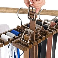 a person is holding onto a rack that has several different colored belts hanging from it