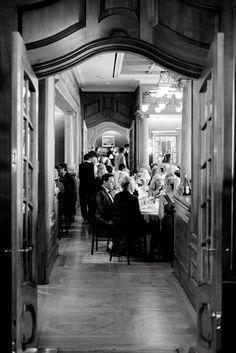 an old photo of people sitting at tables in a restaurant