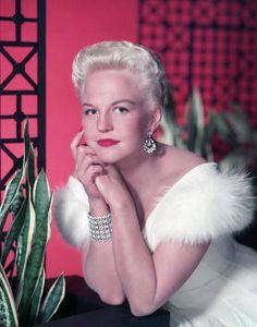 an old photo of a woman in a white dress and fur stole with her hand on her chin