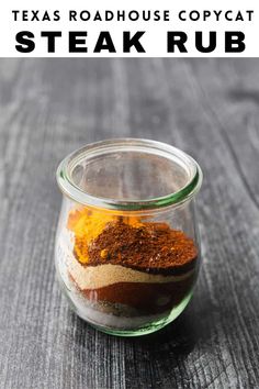 a glass jar filled with spices sitting on top of a wooden table next to the words texas roadhouse copycat steak rub