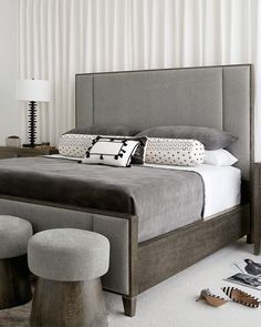 a bedroom with a bed, two stools and a lamp on the side table