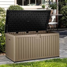 an outdoor storage box in the middle of a yard with grass and flowers around it