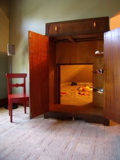 an empty room with a bed in it and a red chair next to the door