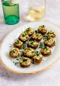 small appetizers are served on a plate next to a glass of white wine