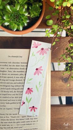 a bookmark with watercolor flowers on it next to a potted plant