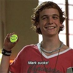 a young man holding a neon green frisbee in his right hand with the words mark sucks on it