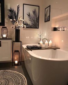 a white bath tub sitting in a bathroom next to two candles and pictures on the wall