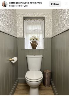 a white toilet sitting in a bathroom next to a window with curtains on the windowsill