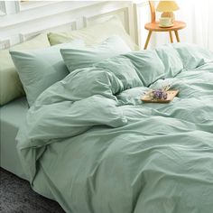 an unmade bed with green sheets and pillows