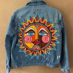 a denim jacket with an image of a woman's face painted on the back