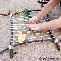 a young child is playing with an art project made out of sticks and branches that have been placed on the ground