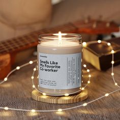 a candle is sitting on a table with string lights around it and a guitar in the background