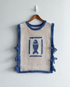 a blue and white knitted sweater hanging on a wall next to a wooden hanger