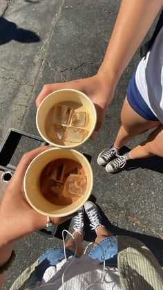 two people holding cups with ice cubes in them