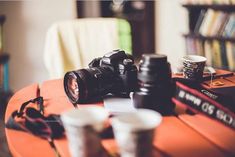 a camera sitting on top of a table next to two cups and a coffee cup