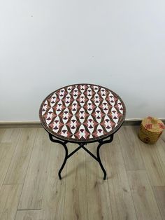 a small table with an unusual design on it next to a wicker basket and white wall