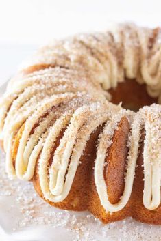 a bundt cake with white icing on a glass plate covered in powdered sugar