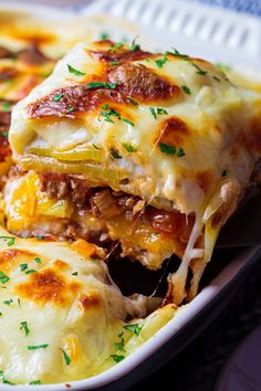 a casserole dish with meat, cheese and sauce on it is shown in a white dish