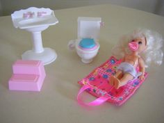 a barbie doll laying on a pink mat next to a sink, toilet and bathtub