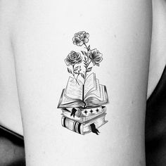 a woman's thigh with a book and flowers tattoo on her left side ribcage