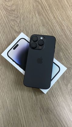 an iphone 11 pro sitting on top of a wooden table next to a white box