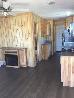 an empty kitchen and living room with wood paneling